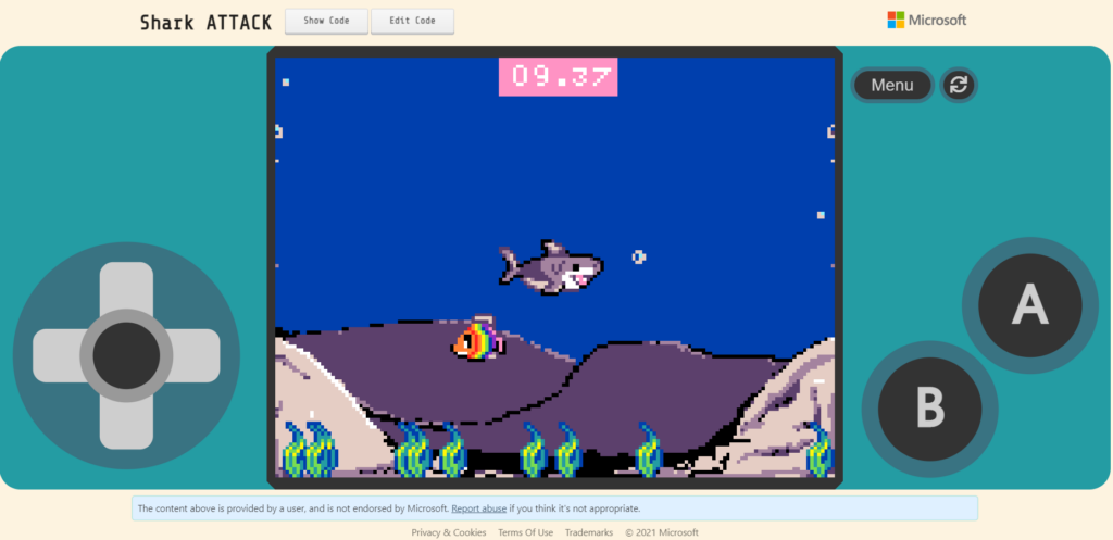 A screenshot of the game I created called Shark ATTACK. It appears on an on-screen emulator, with a pixelated shark in the center of the screen with a rainbow fish swimming below.